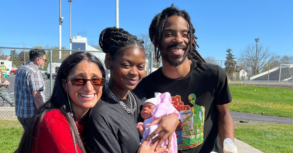 Mona Hanna with two parents, who are holding their recently born infant.